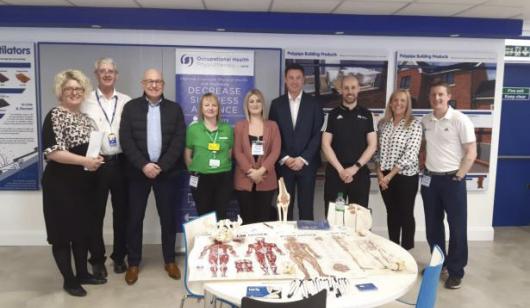 Polypipe employees and external representatives standing behind a table which shows various health and wellbeing literature