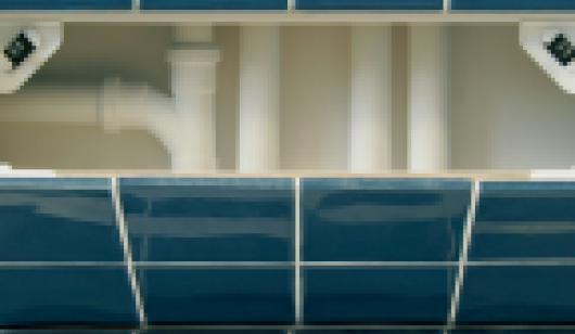 Open blue tiled access panel showing plastic pipework behind
