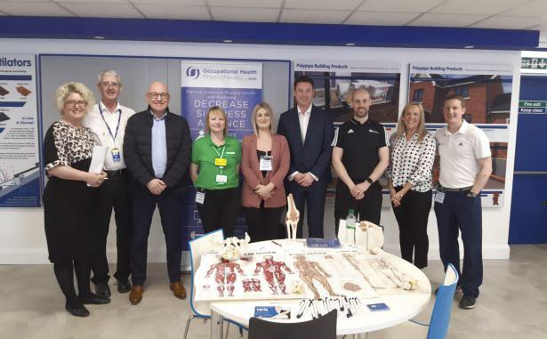 Polypipe employees and external representatives standing behind a table which shows various health and wellbeing literature